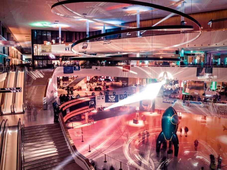 Eingangshalle des Congress Center in Hamburg, fotografiert mit langer Belichtungszeit sodass die Menschen verschwimmen. Klar zu sehen ist die Rakete ("Fairy Dust") am Boden sowie Banner an den Ballustraden.