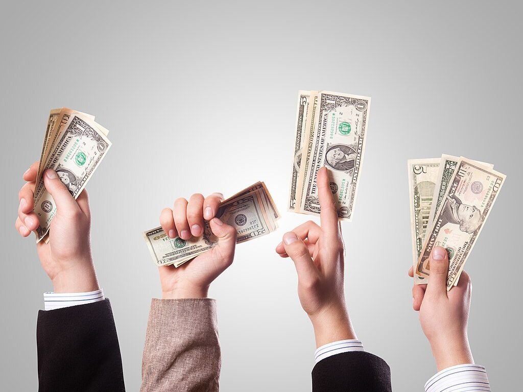 Foto, das vier Hände zeigt, die Dollarscheine in die Luft halten