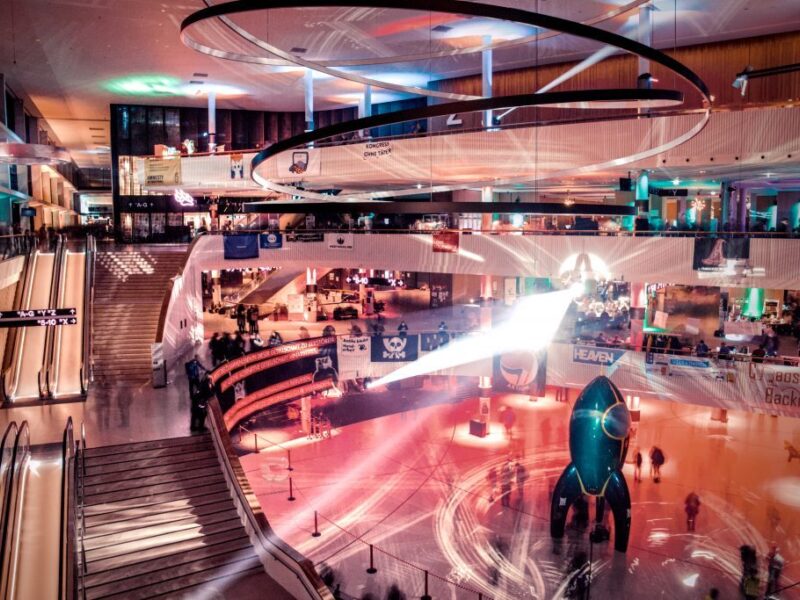 Eingangshalle des Congress Center in Hamburg, fotografiert mit langer Belichtungszeit sodass die Menschen verschwimmen. Klar zu sehen ist die Rakete ("Fairy Dust") am Boden sowie Banner an den Ballustraden.