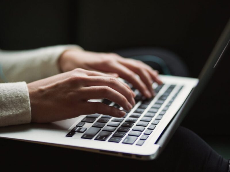 Hände einer Person auf einem Laptop-Keyboard, schreibend