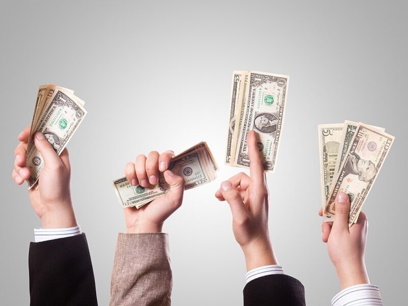 Foto, das vier Hände zeigt, die Dollarscheine in die Luft halten
